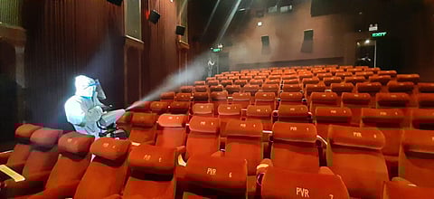 A worker sanitises inside a theatre hall. (Photo | Shekhar Yadav)