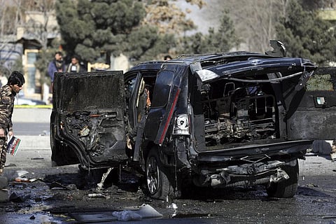Security personnel inspects a body inside a vehicle involved in a bomb attack in Kabul, Afghanistan. (Photo | AP)