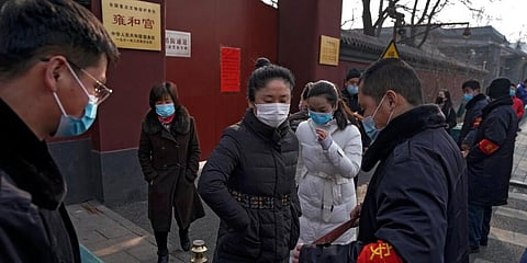 Worshippers wearing face masks to help curb the spread of the coronavirus leave after security guards barricade the closed Yonghegong Lama Temple. (Photo | AP)