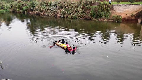 Villagers of Old Athikuppam cross the river while carrying the body of an elderly man for the funeral on Thursday. (Photo | EPS)