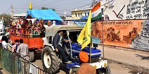 Farmers stand next to their tractors during an ongoing protest against the new farm laws, at the Singhu border in New Delhi. (Photo| ANI)