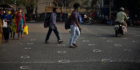 People wearing masks as a precaution against the coronavirus walk on a street marked with circles to ensure social distancing in Kochi. (File photo| AP)