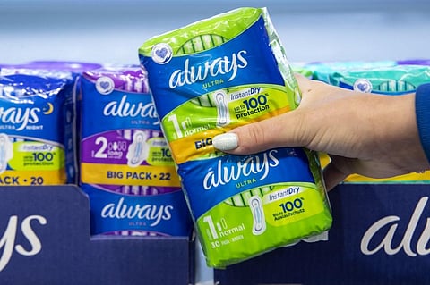 A woman poses with period products on a shelf in a supermarket. (Photo | AFP)