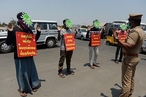 Men wear masks depicting a coronavirus and placards as a punishment enforce by the police. (Photo| AFP)