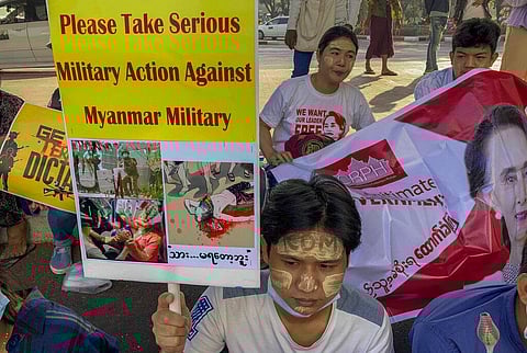 An anti-coup protester holds a placard requesting military action against Myanmar military in Yangon (Photo | AP)