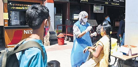 A health worker collects swab sample of a passenger at KSR Railway Station in Bengaluru on Thursday | Shriram BN
