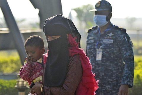 A Rohingya refugee carries a child and walks to board a naval vessel to be relocated to to the island of Bhasan Char, in Chattogram, Bangladesh. (Photo | AP)
