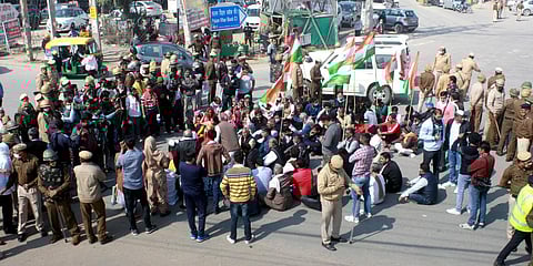 Farmers shout slogans sitting on a road during roadblock-protest on Chakka Jam in Gurugram. (Photo| ANI)
