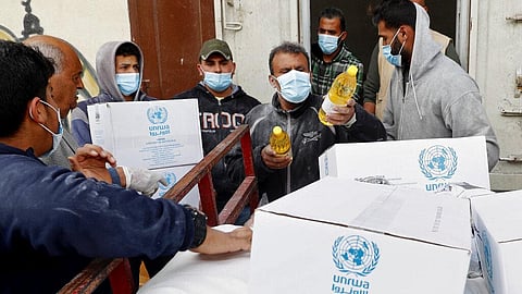 Palestinian workers load food supplies distributed by the United Nations Relief and Works Agency (UNRWA) at the Sheikh Redwan neighborhood of Gaza City.