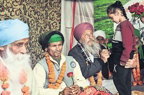 A girl gives roses to protesting farmers on the main stage at the Ghazipur protest site on Sunday | Parveen negi