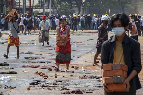 People carry bricks to help anti-coup protesters to build makeshift barricades in Yangon, Myanmar. (Photo | AP)
