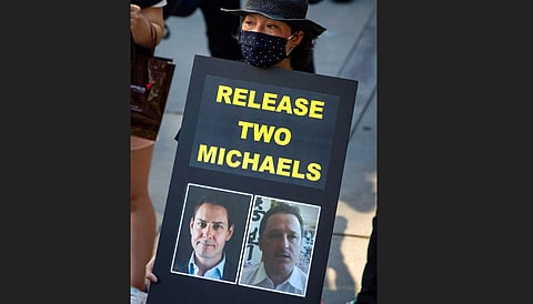A woman holds a sign with images of Michael Kovrig, left, and Michael Spavor, who have been detained in China since December 2018, during a rally in support of Hong Kong democracy. (Photo | AP)