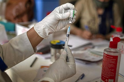 A health worker prepares to administer COVISHIELD vaccine to an elderly man at a government hospital in Noida. (Photo | AP)