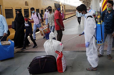 A health worker sanitizes the baggage of passengers as a precaution against COVID-19 at a long distance train station in Mumbai. (Photo | AP)