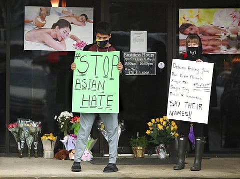 After dropping off flowers Jesus Estrella, left, and Shelby stand in support of the Asian and Hispanic community outside Young's Asian Massage. (Photo | AP)