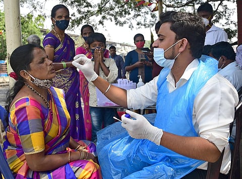 A medical worker collects a swab sample from a passenger at Majestic Bus terminus during the COVID-19 test in Bengaluru. (Photo | Ashishkrishna H P , EPS)