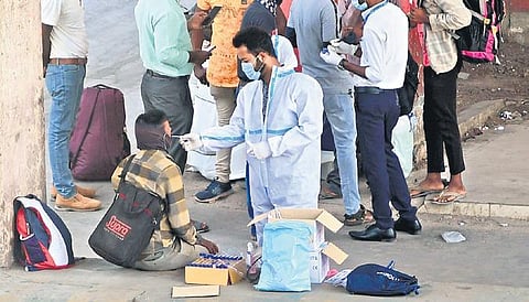 A health worker clad in PPE kit collects swab samples of  passengers at the KSR railway station in Bengaluru from on Sunday | ashishkrishna HP