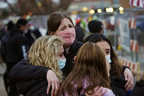 Sophia Kennedy, Kaylynn Devivo, Nirbisha Shetsha and Josie Elowsky comfort each other along a fence put up around the parking lot where a mass shooting took place. (Photo | AP)