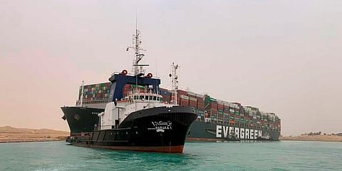 A boat navigates in front of a cargo ship, Ever Given, after it becomes wedged across Egypt’s Suez Canal and blocked all traffic in the vital waterway. (Photo | AP)