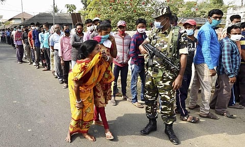A paramilitary jawan guards as people wait to cast their votes at a polling station during the first phase of West Bengal Assembly elections, at Sirshi in Jhargram. (Photo | PTI)