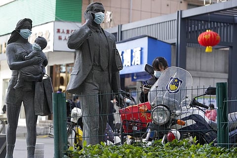 Statues along a street are seen with masks placed on them as a WHO mission team visits Wuhan in central China's Hubei province. (Photo | AP)