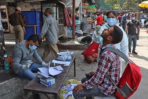 Healthcare workers in PPE kit collect swab sample for COVID-19 testing at a Bus Stand in Jammu. (Photo | ANI)