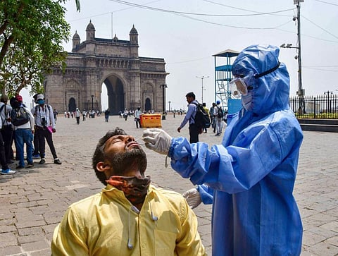 A health worker, wearing PPE kit, conducts COVID-19 test of a person at the Gateway of India in Mumbai. (File Photo | PTI)