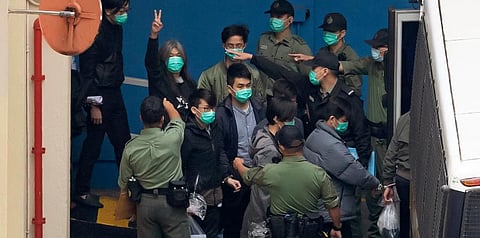 Former lawmaker Leung Kwok-hung (Second L) shows a victory sign and some of the 47 pro-democracy activists are escorted by CS officers to a prison van in Hong Kong. (Photo | AP)