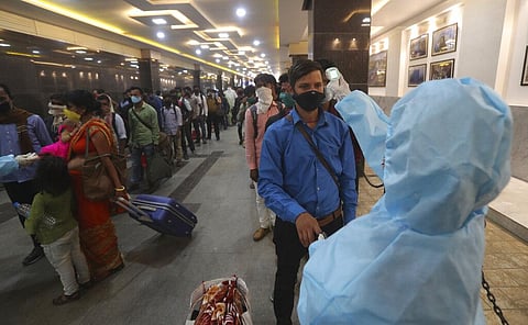 Passengers line up to get their temperatures checked at a train station in Mumbai, Maharashtra. (Photo | AP)