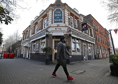 A man walks past the Duke of Sussex pub with a sign depicting the image of Britain's Prince Harry and his wife Meghan. (Photo| AP)