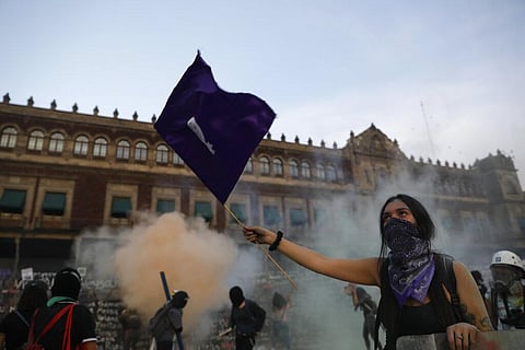 A woman waves a feminist flag as demonstrators attempt to storm the National Palace during a protest against gender violence, in Mexico City. (Photo | AP)