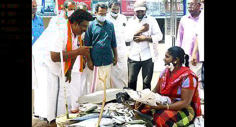 NDA candidate P Sudheer chats with a fish vendor during campaign at Attingal market. (Photo | Express)
