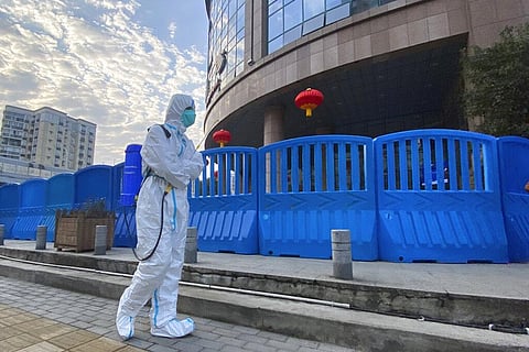 A worker in protectively overalls and disinfecting equipment walks outside the Wuhan Central Hospital. (Photo | AP)