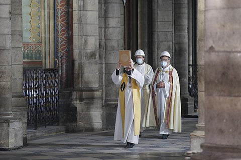Notre Dame rector Patrick Chauvet leads a procession, wearing protective helmets, on Maundy Thursday, in Notre Dame Cathedral almost two years after a massive fire left it ravaged. (Photo | AP)