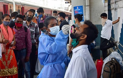 A health worker takes a swab sample of a passenger at Dadar railway station amidst spike in Covid-19 cases, at Dadar. (Photo | PTI)