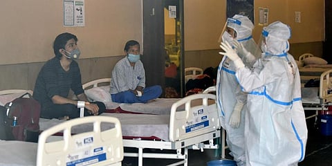 Healthcare workers wearing a PPE kit instruct the COVID-19 patients at a temporary converted isolation ward for COVID-19 patients, at Shehnai Banquet Hall in New Delhi. (Photo | ANI)