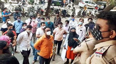 Police personnel stand guard as people stage protest over shortage of Remdesivir injection at chemist centers at Shukrawar Peth area in Pune. (Photo | ANI)