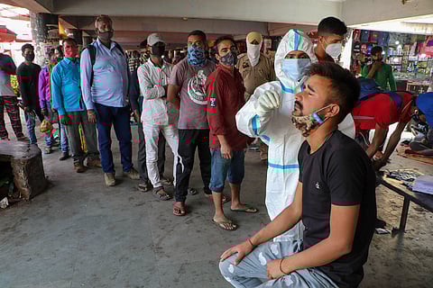 A health worker takes a nasal swab sample of a passenger to test for COVID-19 , amid a countrywide spike in coronavirus cases, at a bus stand in Jammu, Wednesday. (Photo | PTI)