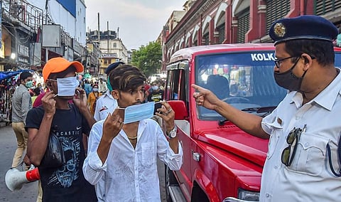 A policeman asks people to wear protective face masks, as coronavirus cases surge across the country, at New Market area of Kolkata. (Photo | PTI)