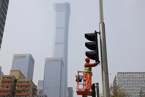 A worker installs new traffic lights at a junction in Beijing on Thursday, April 15, 2021. (Photo | AP)