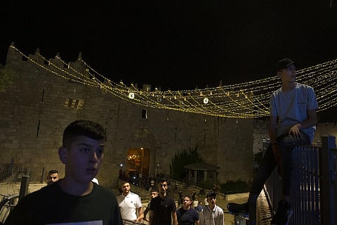 Palestinian youth gather near the Damascus Gate to the Old City of Jerusalem as they watch Israeli police disperse a crowd on Monday. (Photo | AP)