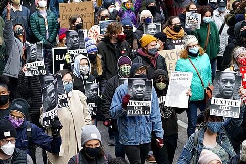 People hold signs as they march near the Hennepin County Government Center during a rally in Minneapolis on Monday, April 19, 2021. (Photo | AP)
