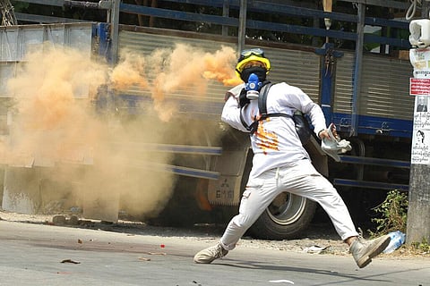 An anti-coup protester throws a smoke bomb against police during a crackdown in Thaketa township in Yangon, Myanmar. (File photo | AP)
