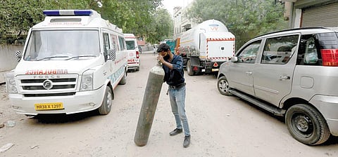 A man carries a cylinder filled with medical oxygen at a plant in New Delhi on Wednesday | Shekhar Yadav
