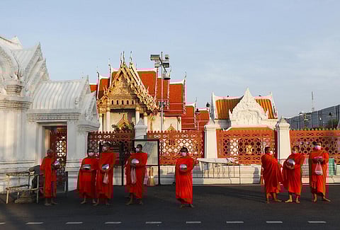 Buddhist monks wearing face masks to protect themselves from the coronavirus wait in line to receive alms during a morning alms offerings in front of Marble Temple in Bangkok. (Photo | AP)