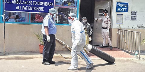 A health worker moves oxygen cylinders at a hospital in New Delhi on Friday. (Photo | Parveen Negi, EPS)