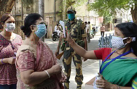 A voter undergoes thermal screening during the seventh phase of Bengal election in Kolkata on Monday. (Photo | PTI)