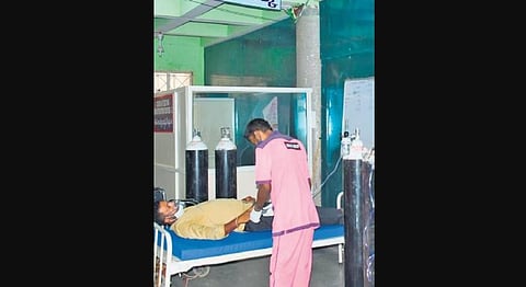 A Covid patient waits for treatment at Karimnagar government hospital, near a set of oxygen cylinders.