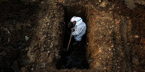 A man in protective suit digs earth to bury the body of a person who died of COVID-19 in Guwahati. (Photo| AP)