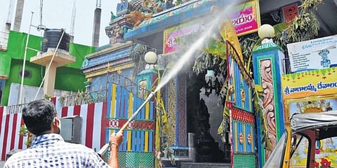 A civic worker sprays disinfectant on the entrace of a temple in Tirupati city. (Photo| Madhav K, EPS)